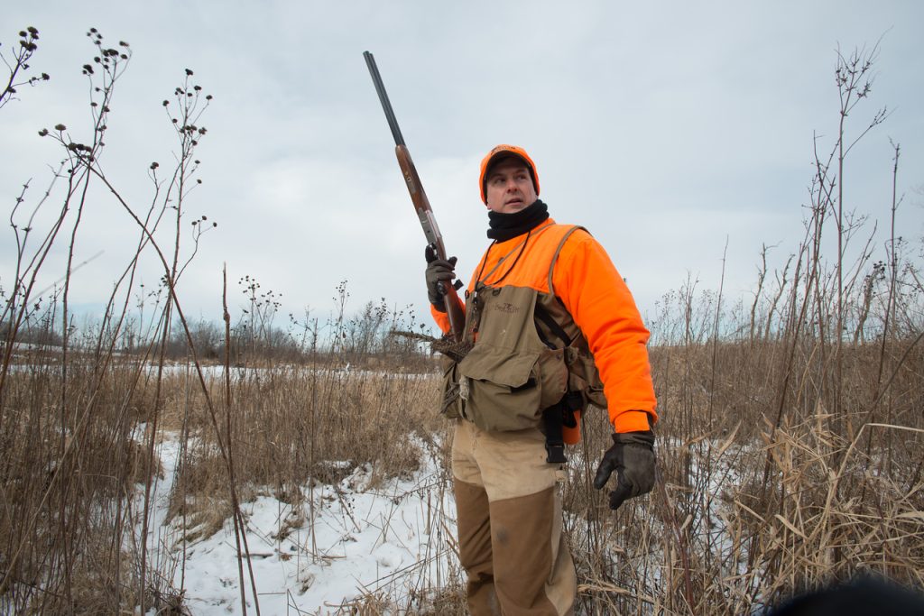 hunter standing in winter grass field