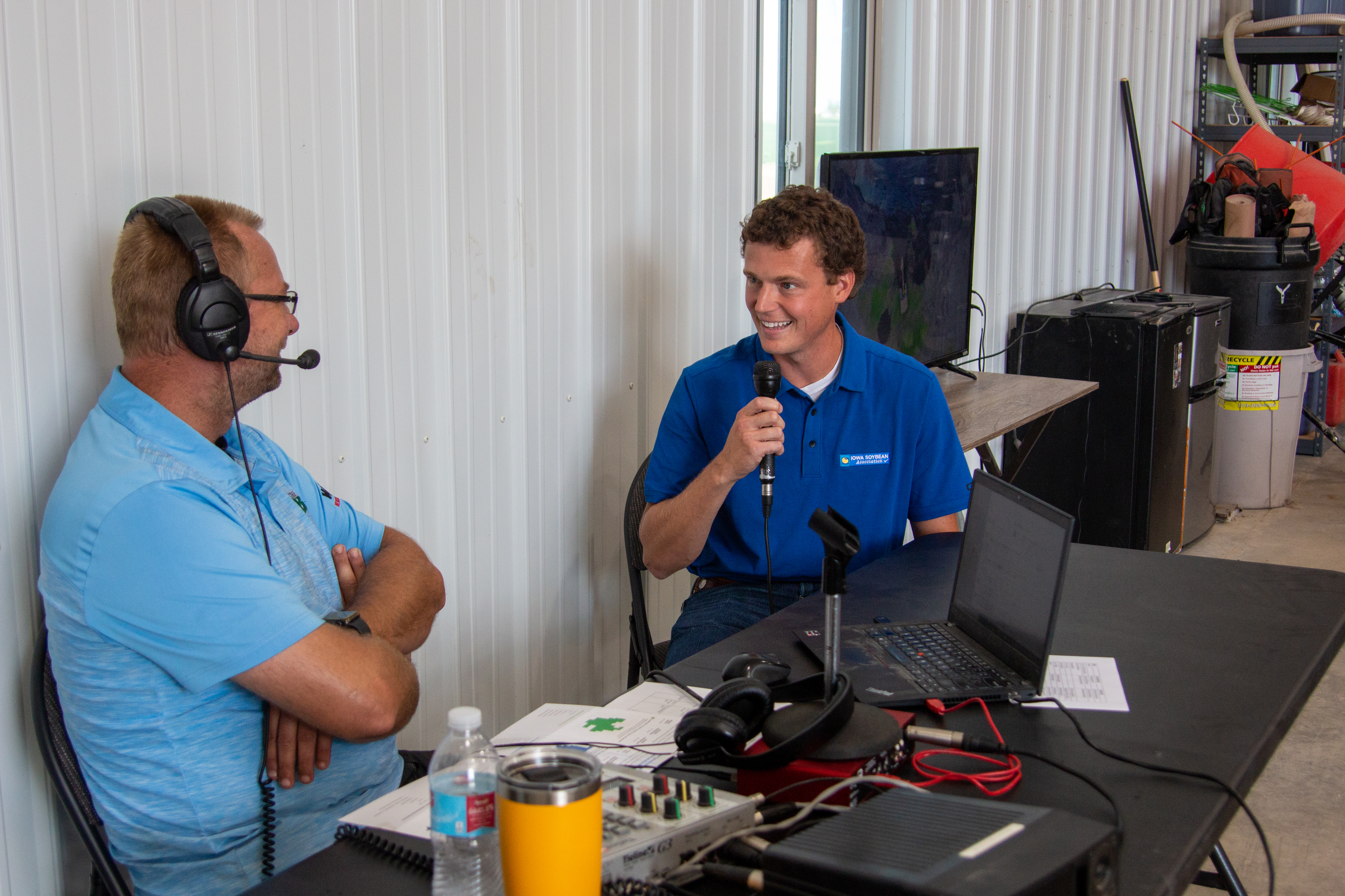 host and interviewee next to radio equipment in a shed