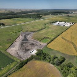 A wetland construction site is seen in aerial view. The cleared-out site is surrounded by farmland.