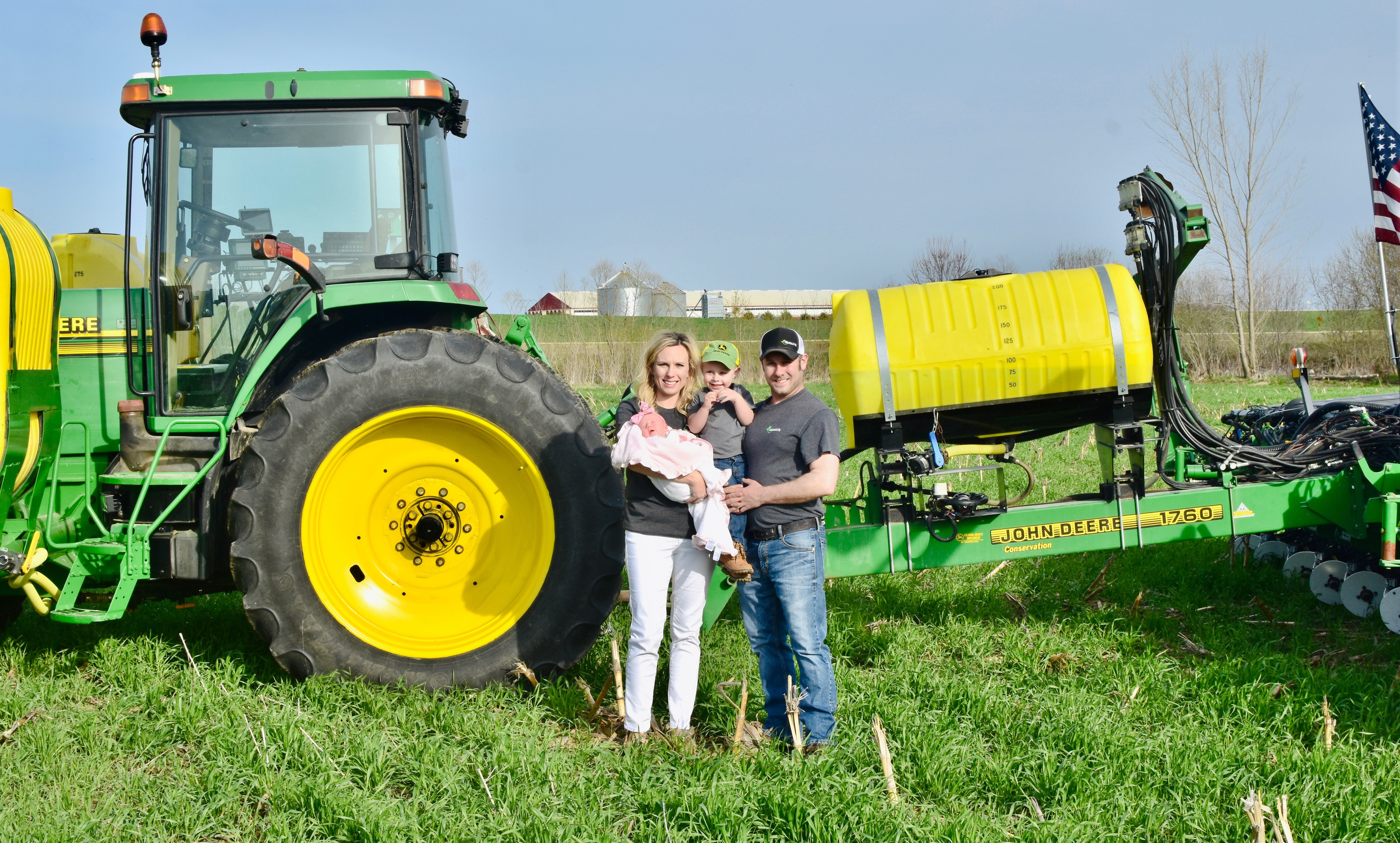 Gibbs family poses in front of a tractor in a field