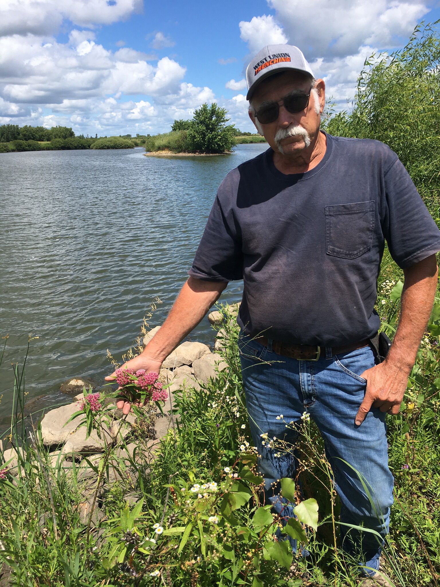farmer stands in front of pond