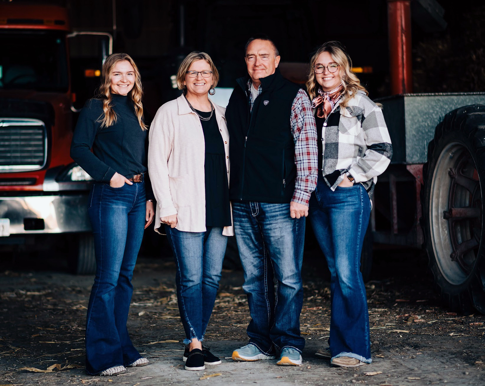 Kerri Bell and her family - a husband and two daughters - smile for a family photo in the entrance of a farm storage shed.