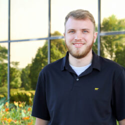 Tanner puls stands in greenhouse